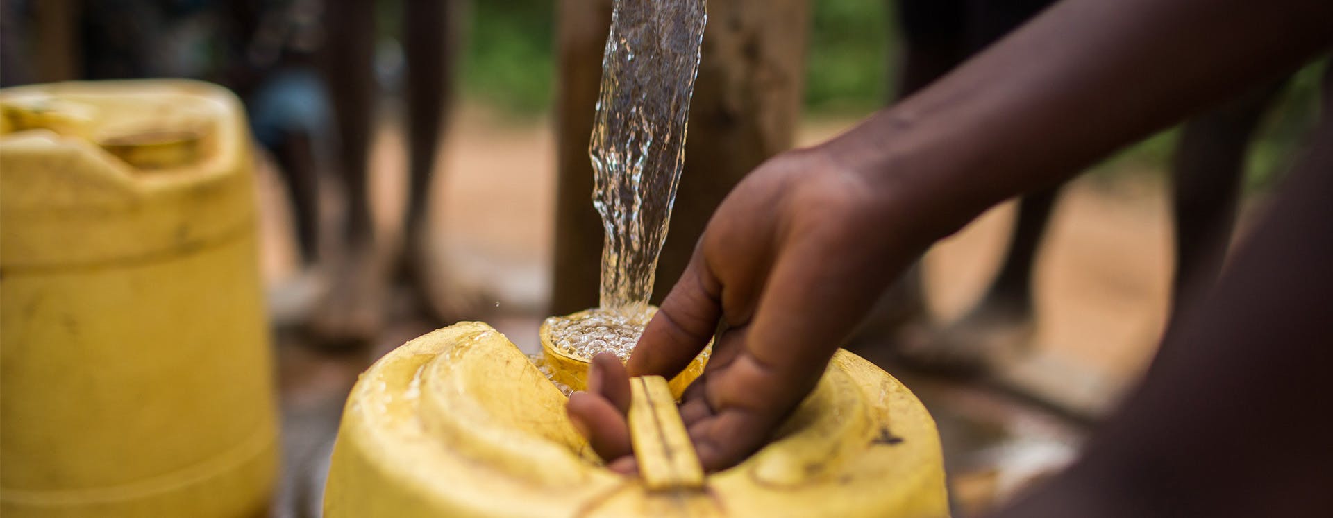 Filling jerry can with water from charity: water well.