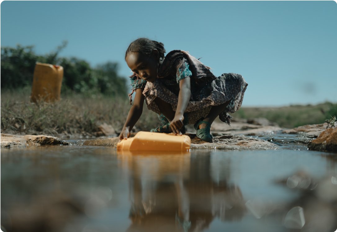 Girl filling jerry can with water from a pond.